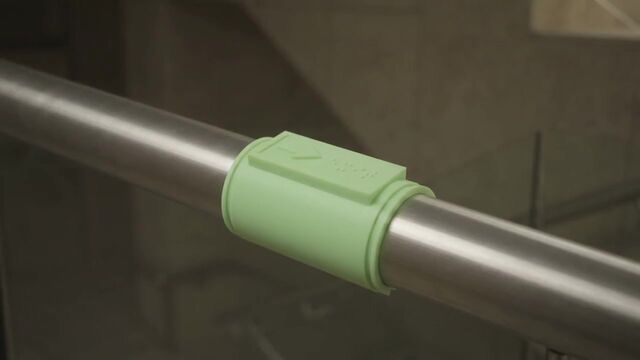 A pale green DALIL clip on a steel rail in daylight. With the lights off it glows.