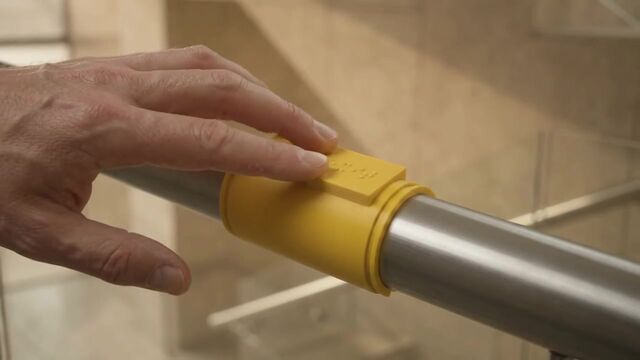 A hand slides along a steel rail and meets a yellow DALIL clip.